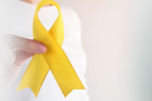 手持金色丝带的年轻女性关注儿童癌症.